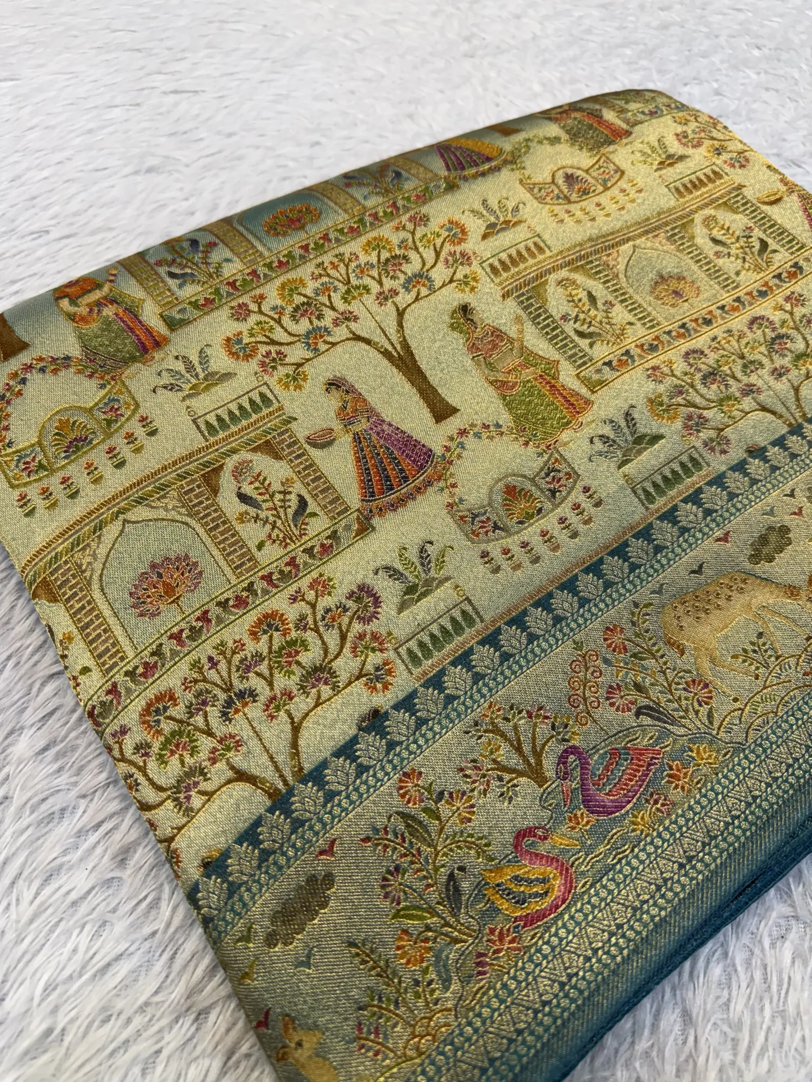 E0870119 – Gold Banarasi Tissue Saree with Teal Scenic Border